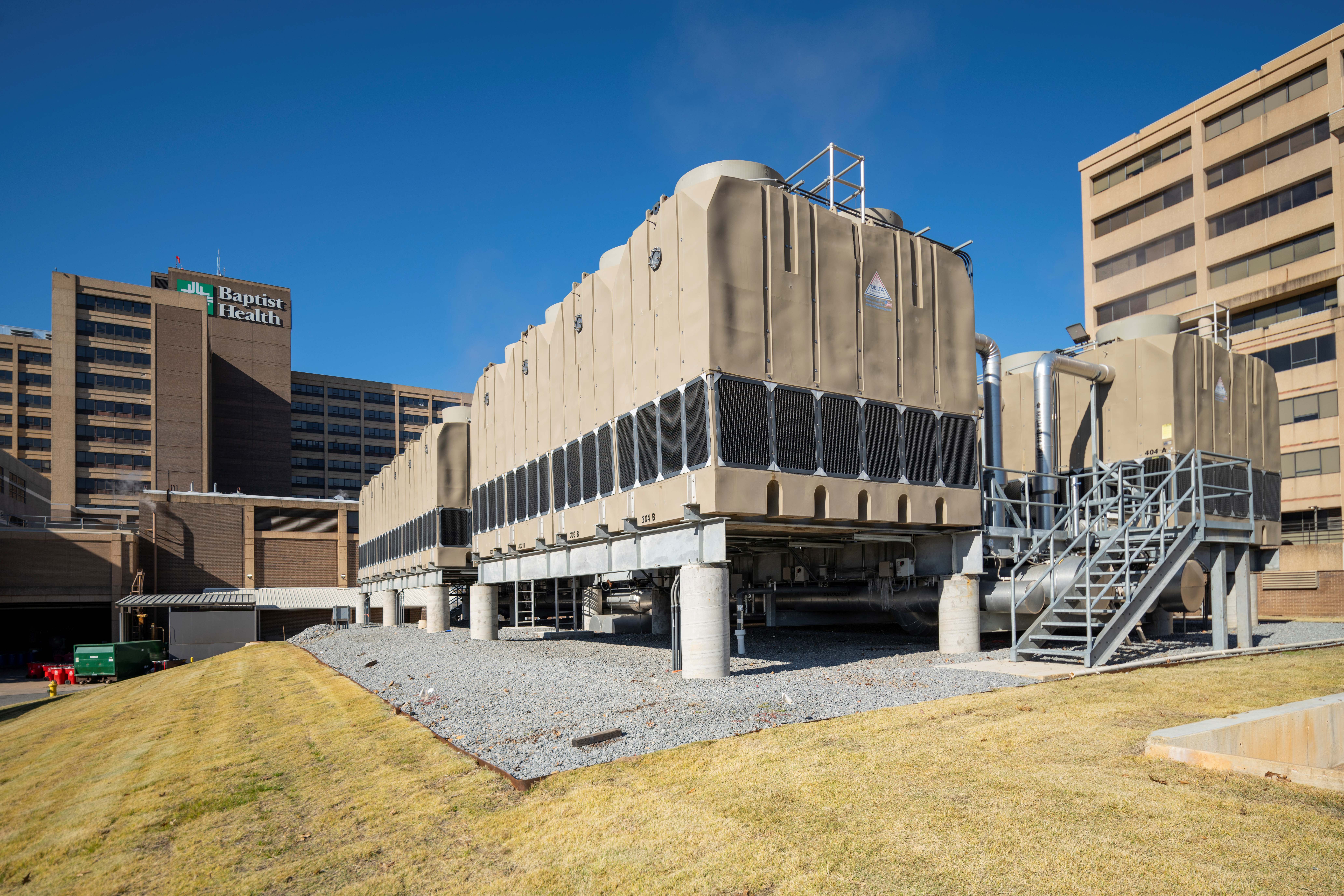 Exterior view of the cooling towers outside of Baptist Health Medical Center–Little Rock, with a view of the hospital in the background.