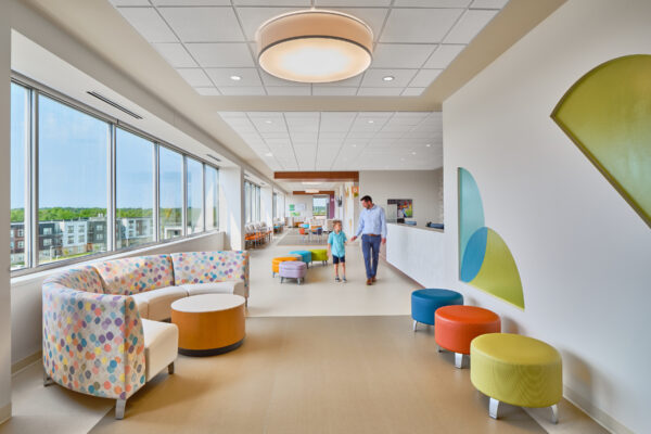 Creating Ambulatory Surgery Centers That Succeed for Patients, Physicians and Investors A bright hallway featuring colorful cushion seats and large windows.